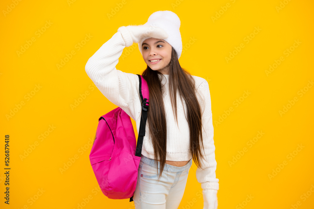 Back to school. Teenager schoolgirl with warm hat and sweater on yellow isolated studio background. Winter school. Back to school. Teenager schoolgirl with warm hat and sweater on yellow isolated studio background. Winter school.
