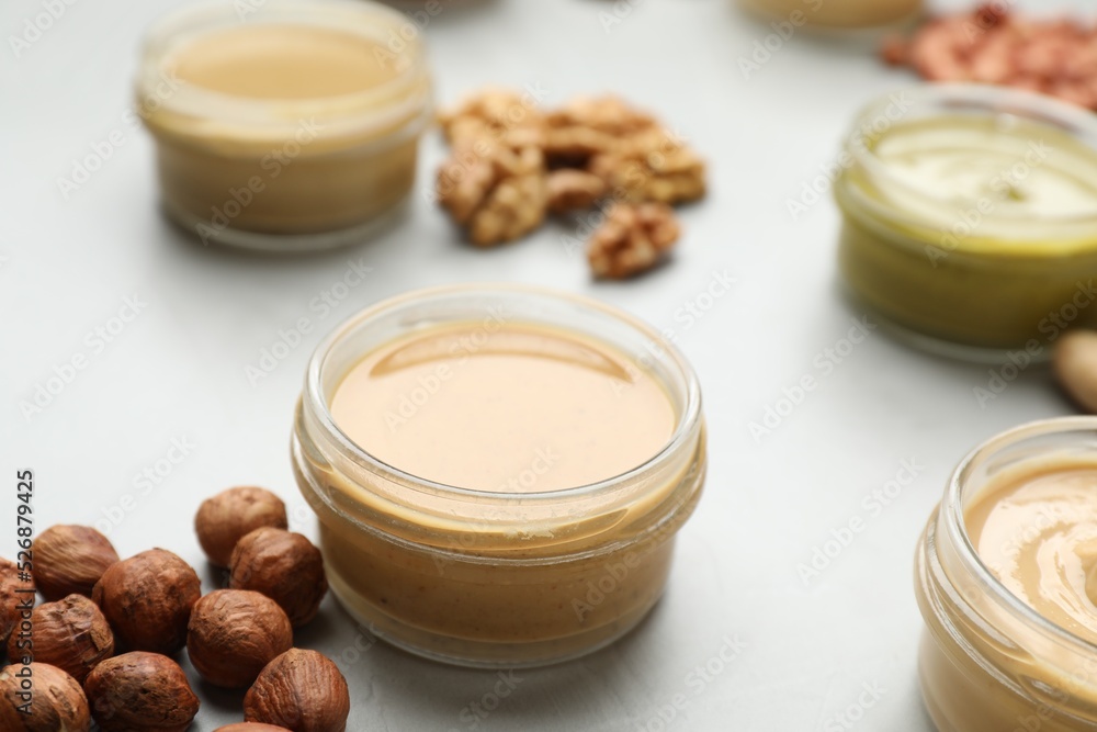 Fototapeta premium Different types of delicious nut butters and ingredients on light table, closeup