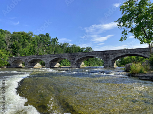Five-span stone bridge in Pakenham, Ontario with rapids in the foreground and forested shores