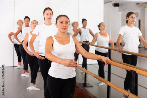 Group of women standing in row together while doing ballet dance moves.