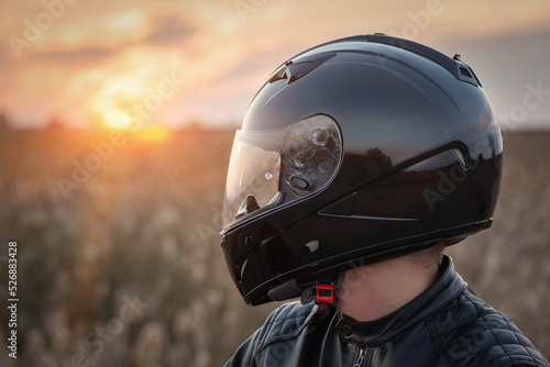 Biker in the helmet in the sunset rays close up portrait.
