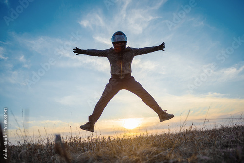  A happy motorbike in the helmet is jumping among a field at sunset. Freedom.
