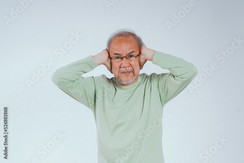 Asian senior elderly old man hands covering your ear to mute loud noise her unhappy sound expression on the isolated white background