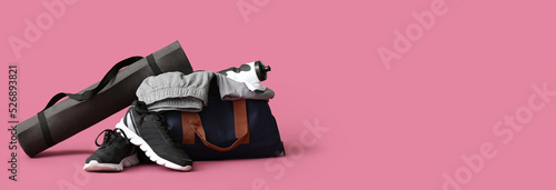 Sports bag, shoes and yoga mat on pink background with space for text