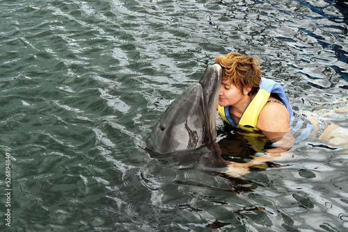 A woman and a dolphin swim in the dolphinarium.