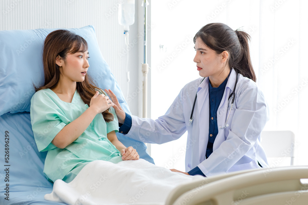 Obraz premium Asian young professional female practitioner doctor in white lab coat with stethoscope holding touching checking monitoring patient injury arm and muscle while laying down on bed in hospital wardroom