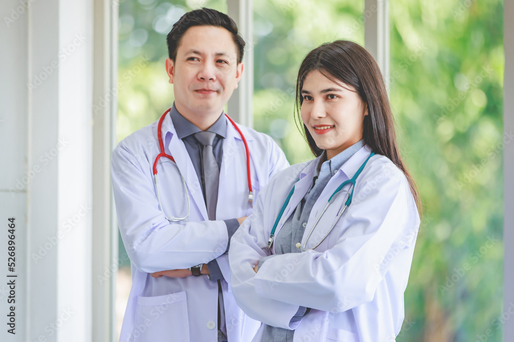 Asian young cheerful professional male and female intern practitioner doctor colleague in white lab coat uniform with stethoscope standing smiling together holding patient paperwork document folder Asian young cheerful professional male and female intern practitioner doctor colleague in white lab coat uniform with stethoscope standing smiling together holding patient paperwork document folder