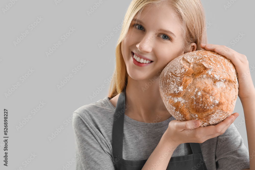 Young woman with fresh bread on grey background, closeup Young woman with fresh bread on grey background, closeup