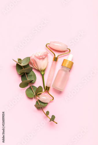 Fototapeta Naklejka Na Ścianę i Meble -  Facial massage tool with cosmetic dropper bottle, eucalyptus and rose on pink background