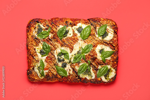 Tasty Italian pie with mozzarella and pesto sauce on red background