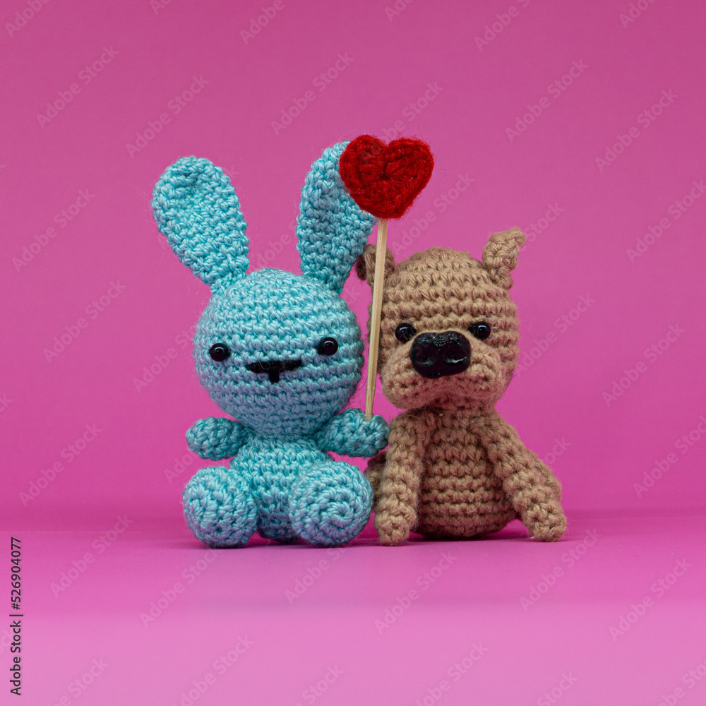 Fototapeta premium Amigurumi of rabbit and dog with a heart, on pink background.