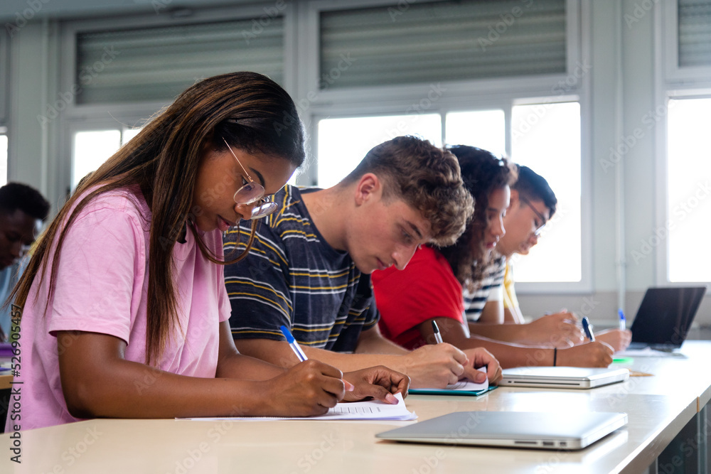African american teen high school student writing in class. Group of college students taking notes in class. African american teen high school student writing in class. Group of college students taking notes in class.