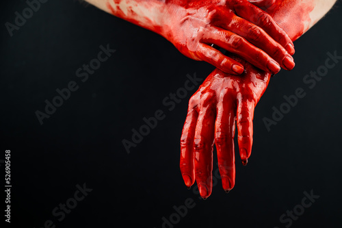 Women's hands in blood on a black background.