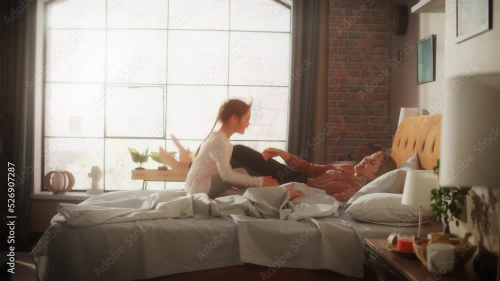 Adorable Little Girl Having Fun at Home with Young Beautiful Mother. Family Playing at Home, Cheerfully Jumping on Bed in Stylish Loft Apartment with Big Window. Happy Childhood. Slow Motion Footage. Adorable Little Girl Having Fun at Home with Young Beautiful Mother. Family Playing at Home, Cheerfully Jumping on Bed in Stylish Loft Apartment with Big Window. Happy Childhood. Slow Motion Footage.
