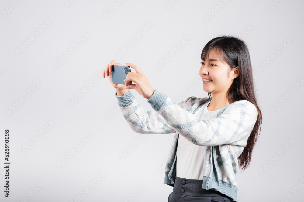 Woman excited holding smartphone to shooting selfie photo front camera studio shot isolated white background, happy young female smiling taking photography by mobile phone on mobile phone