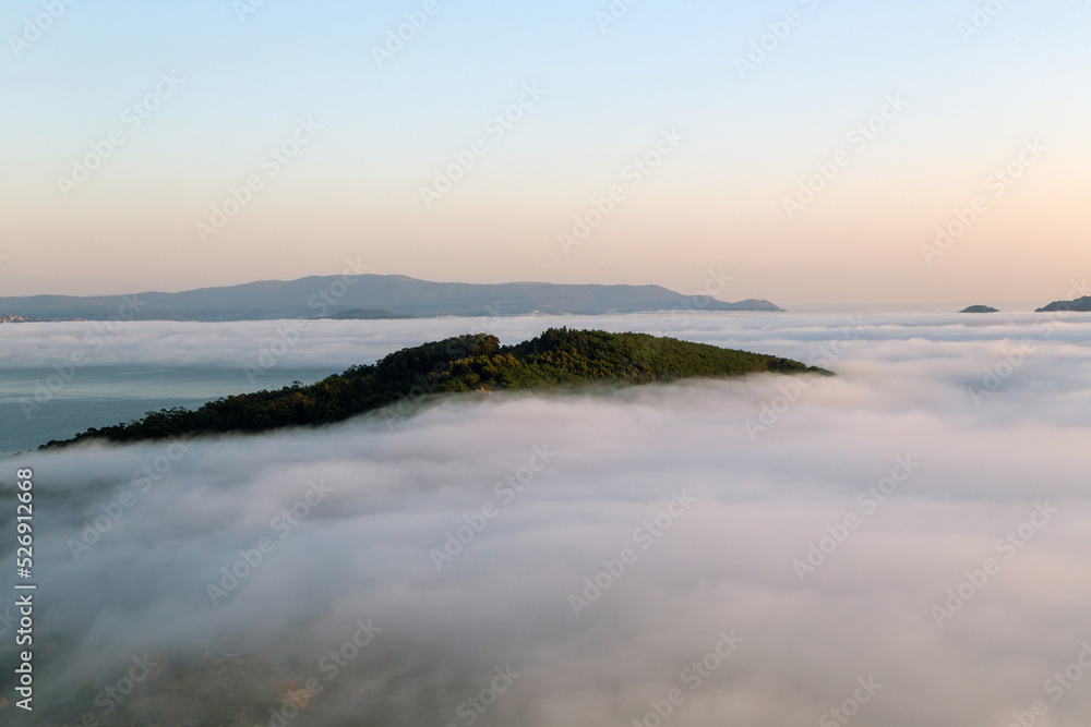 Paisaje costero. En un mar de niebla sobresale una porción de cabo Home. Rías Baixas, Galicia, España.