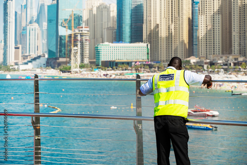Photography Rear view of a male security guard looking at the skyline of a modern city