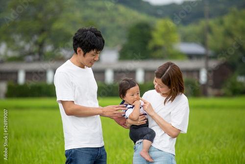 帰省先の田舎、で赤ん坊をあやす若い日本人の家族　故郷の田んぼ、あぜ道で撮影 タイトル変更 © kazoka303030
