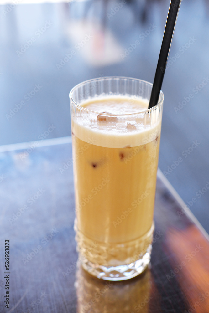 A glass with latte and black straws stands on a table with a metal coating on the summer terrace of a cafe A glass with latte and black straws stands on a table with a metal coating on the summer terrace of a cafe