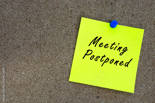 Принти на полотні Meeting postponed on yellow stick note and pinned to a cork notice board