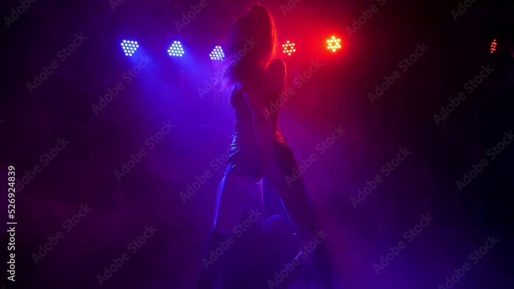 Two women dancing around the pole by the light of colorful lights. Pole dance. Two women dancing around the pole by the light of colorful lights. Pole dance.