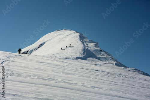 Mountain climbers climbing sunny, snowy mountain peak, Selkirk Mountains, Canada
