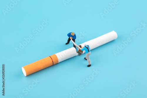 Miniature scene worker sawing off cigarette