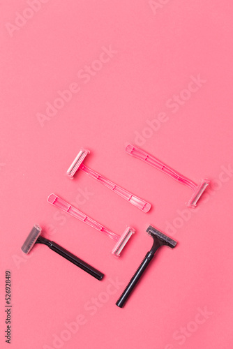 Female Shaving Concepts. Flat-Lay Image of Various Women's Colorful Pink and Black Disposable Razors Shavers Placed in Different Directions On Pink Coral Background