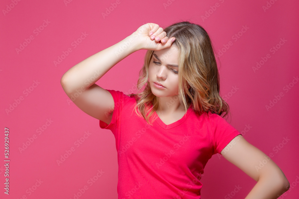 One Beautiful Sad Depressed Caucasian Girl in Pink T-Shirt Posing in Summer Shorts With Lifted Hand Thinking Against Coral Pink Background.
