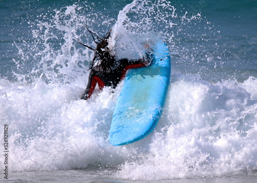 Young boy or girl warming up on the surfboard with the leash on