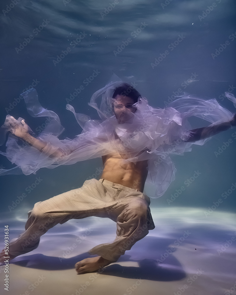 young man in white ribbons and trousers underwater in the pool on a dark background young man in white ribbons and trousers underwater in the pool on a dark background