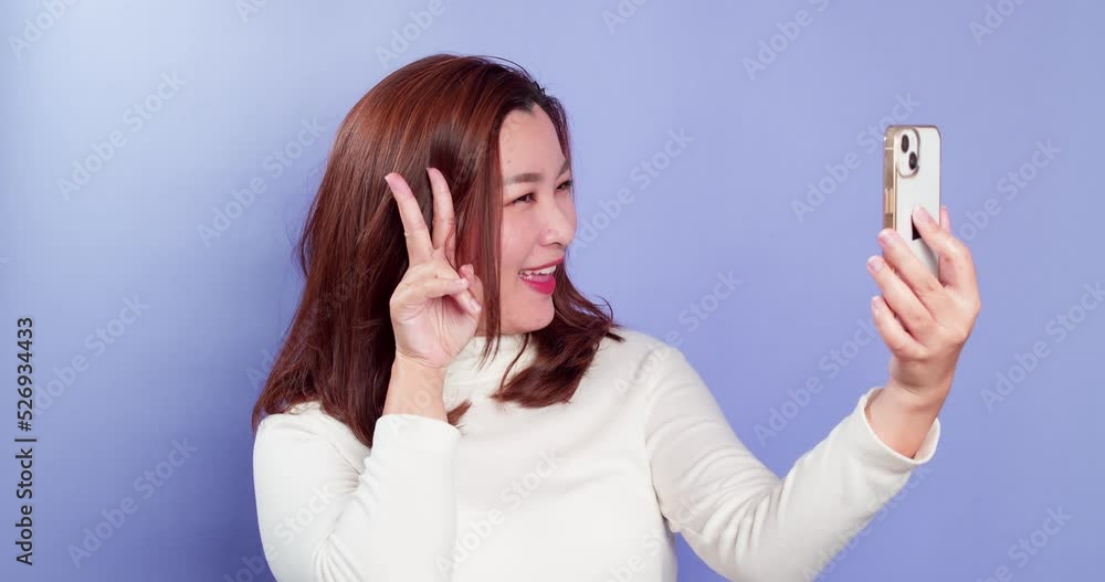 Young beautiful woman using her phone for portrait selfies and a happy lifestyle at home on purple background Young beautiful woman using her phone for portrait selfies and a happy lifestyle at home on purple background
