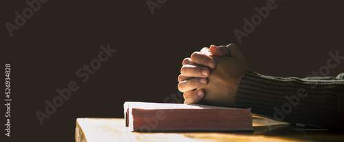 Photo Hands praying of christian put on holy bible with light in morning at wooden table
