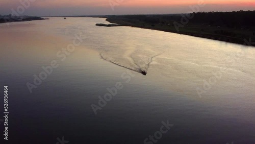 Small motorboat traveling across the Paraguay River at sunset.  photo