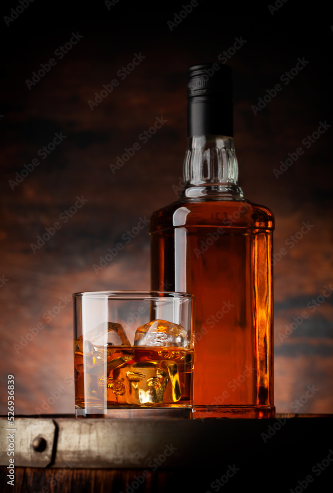 Glass of whiskey with ice cubes and bottle Glass of whiskey with ice cubes and bottle