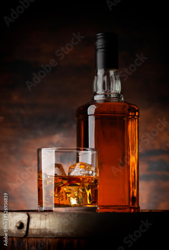 Glass of whiskey with ice cubes and bottle © karandaev