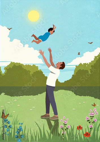 Father throwing playful son overhead in sunny, idyllic meadow
 photo