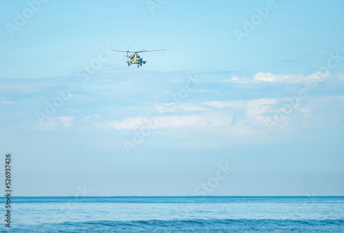 Military helicopter flying overhead on a clear day above the sea. attack helicopter flying the sky, with missiles, rockets and machine gun.