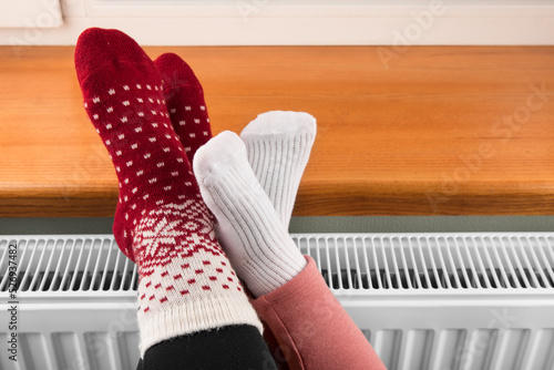 a little girl warms her hands and feet on a radiator