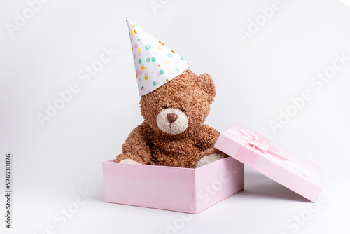 a teddy bear in a pink gift box celebrates a birthday on a white background, isolated