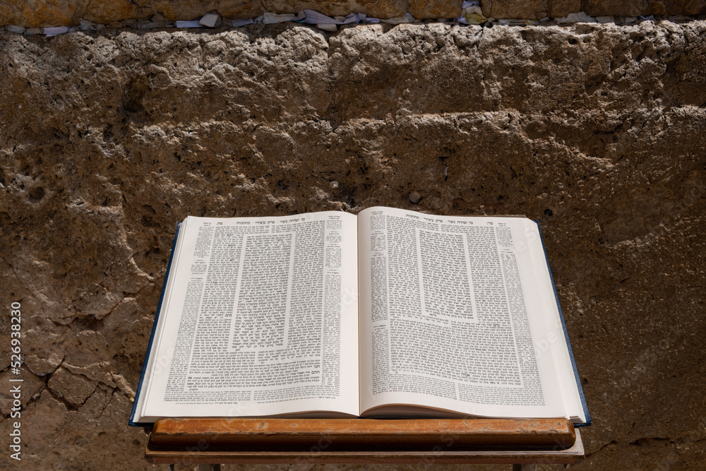 Obraz premium A large volume of the Jewish Talmud open to the text from the tractate Ketubot rests on a prayer stand in front of the Western Wall in Jerusalem.