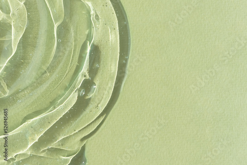 Transparent serum gel with hyaluronic acid for the face on a green background. The texture of a cosmetic product with oxygen bubbles. Wellness and beauty concept.