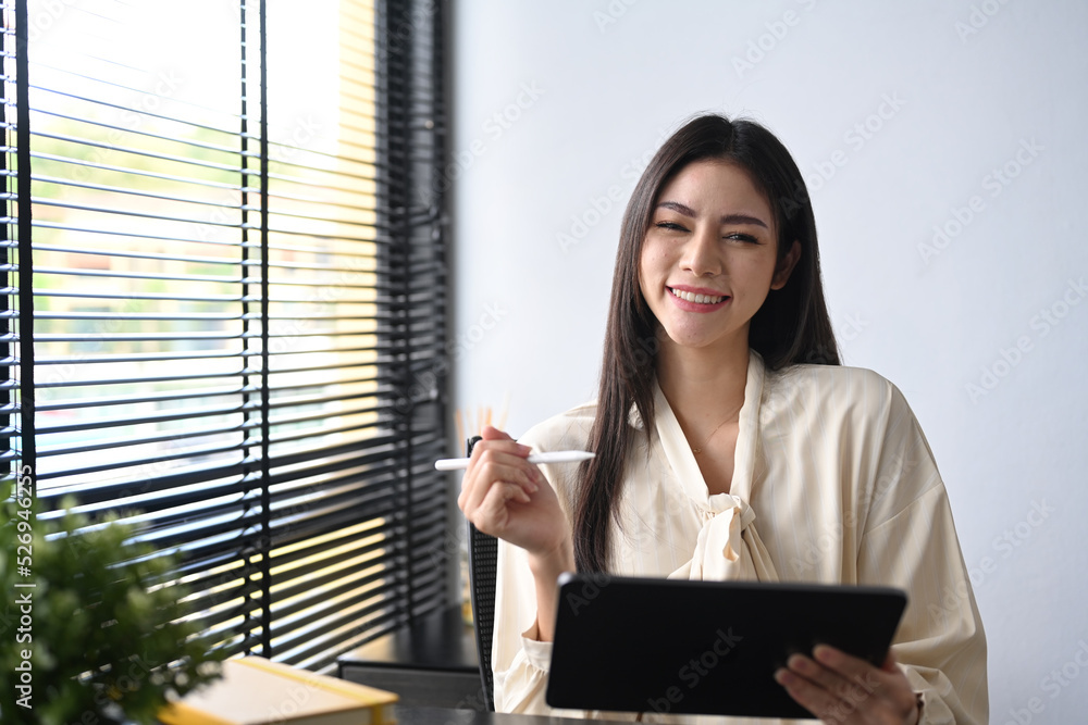 Small business entrepreneur sitting in her personal office and using digital tablet for checking financial data Small business entrepreneur sitting in her personal office and using digital tablet for checking financial data