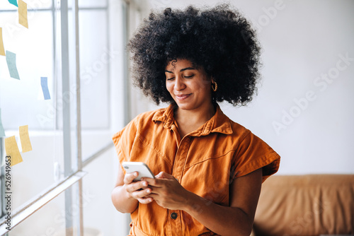 Black businesswoman using a smartphone in a creative office photo