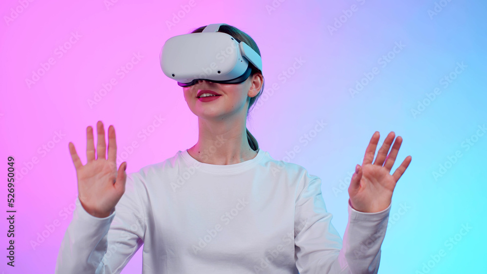 Female model in white clothes gesture hands wearing vr glasses isolated over colorful background Female model in white clothes gesture hands wearing vr glasses isolated over colorful background