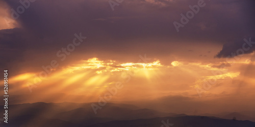 Beautiful summer mountain landscape, clouds and sun rays at bright yellow sunset © olezzo