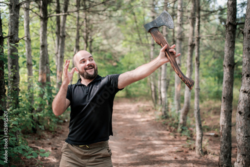 A bearded man holds an axe and raises it up. Winning stance