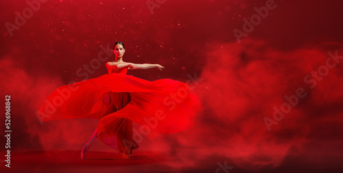 Bilde på lerret A young graceful ballerina, dressed in pointe shoes and a weightless red skirt, demonstrates her dancing skills