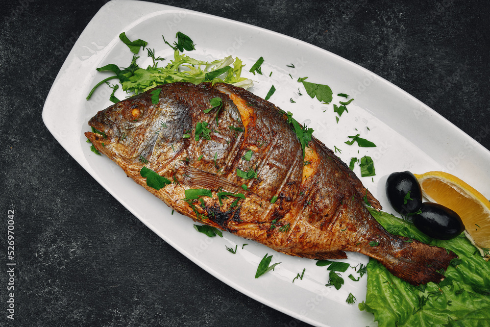 Dorado fish grilled with herbs, on a dark background Dorado fish grilled with herbs, on a dark background