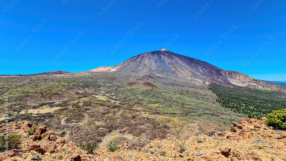 Scenic view on volcano Pico del Teide seen from Riscos de la Fortaleza, Mount El Teide National Park, Tenerife, Canary Islands, Spain, Europe. Hike via La Canada de los Guancheros dry desert plain Scenic view on volcano Pico del Teide seen from Riscos de la Fortaleza, Mount El Teide National Park, Tenerife, Canary Islands, Spain, Europe. Hike via La Canada de los Guancheros dry desert plain
